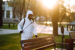 A man wearing special protective disinfection suit sprays sterilizer in the public place. Covid -19.