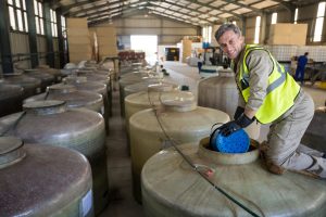 Portrait of happy worker removing oil from tank in factory